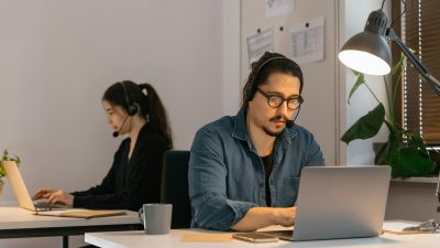 Two call center employees working diligently with headsets in the office.