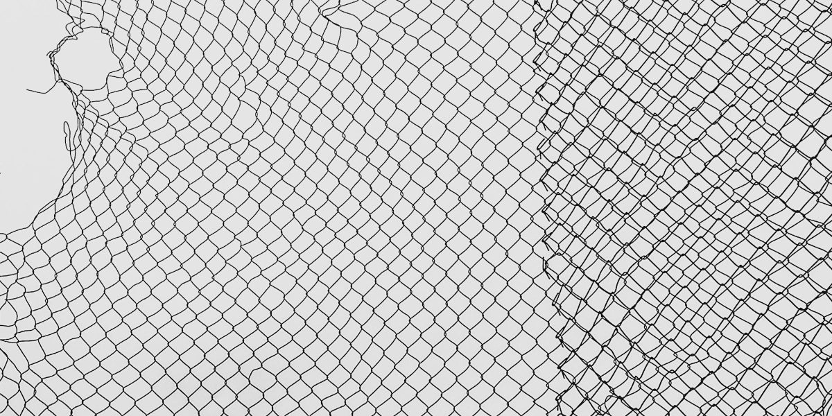 A close-up view of a torn, black safety net with intricate patterning against a white background.