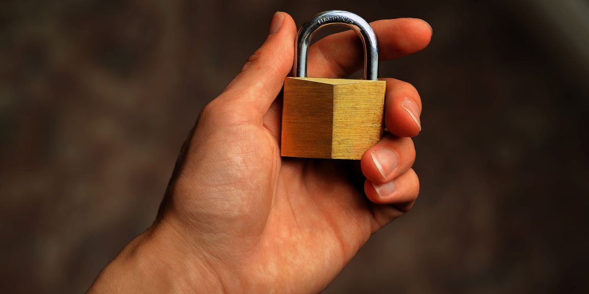 Hand holding a brass padlock symbolizing password security