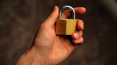 Hand holding a brass padlock symbolizing password security